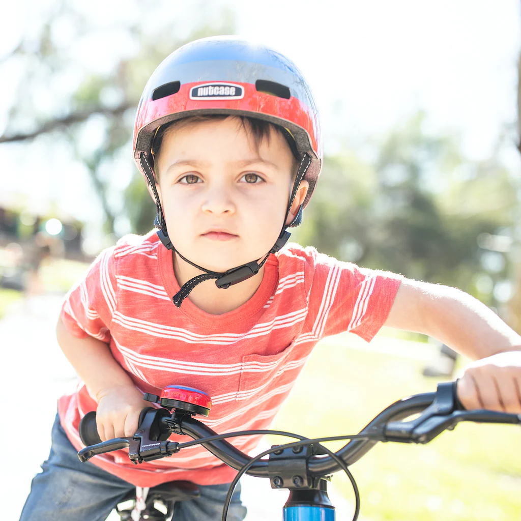 a-small-boy-smiling-while wearing the nutcase little nutty helmet